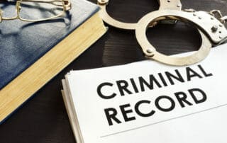 criminal record documents on desk with book and handcuffs